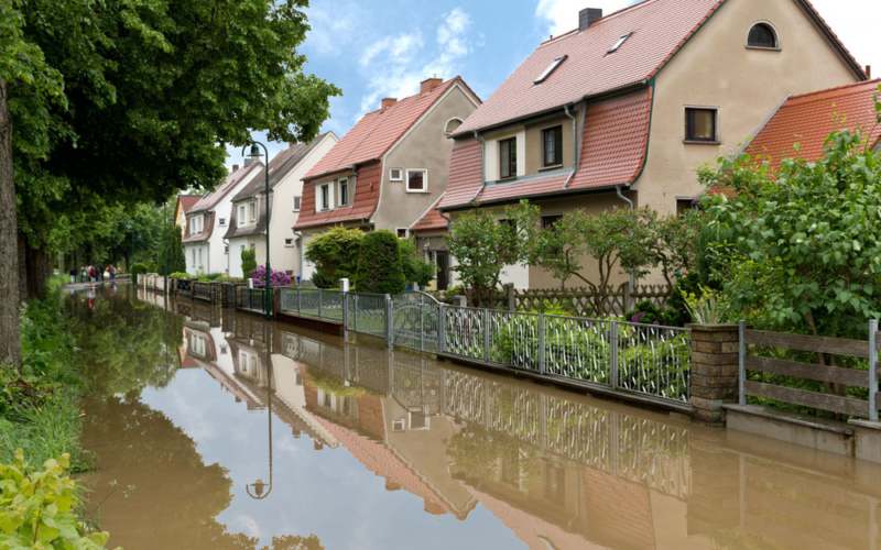 Eine überschwemmte Straße, die an Vorgärten grenzt
